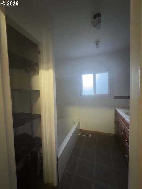 bathroom featuring vanity, a bath, and tile patterned floors