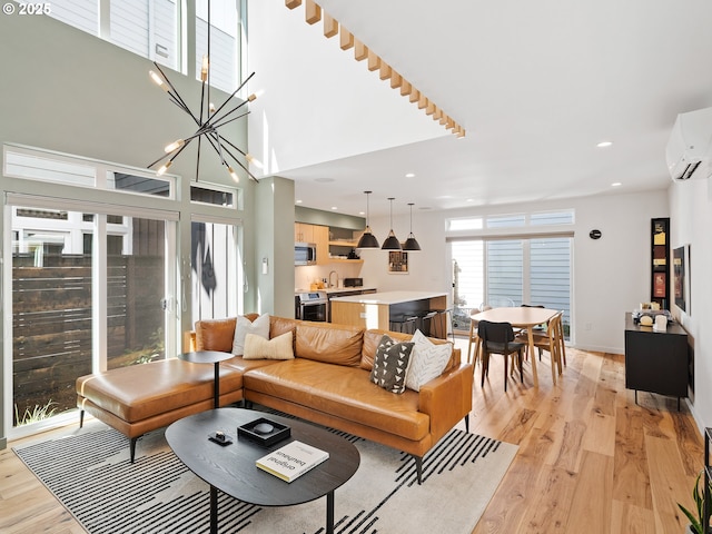 living room featuring a chandelier, recessed lighting, a high ceiling, light wood-type flooring, and a wall mounted air conditioner