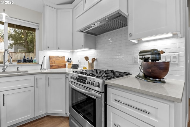 kitchen with white cabinets, gas range, backsplash, sink, and custom exhaust hood