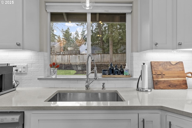 kitchen with dishwasher, sink, tasteful backsplash, and white cabinets