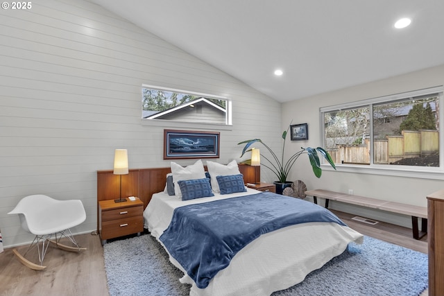 bedroom with light wood-type flooring, lofted ceiling, and multiple windows