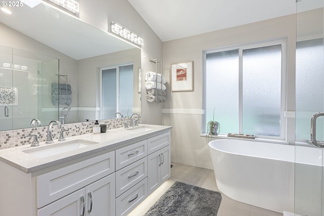 bathroom featuring a healthy amount of sunlight, vaulted ceiling, a bathtub, and vanity