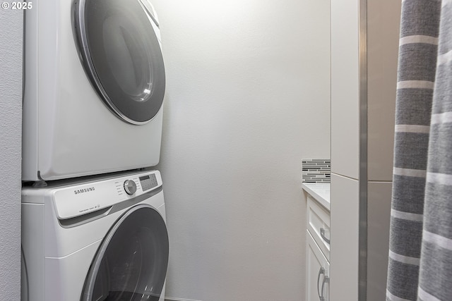 laundry area with cabinets and stacked washer and clothes dryer