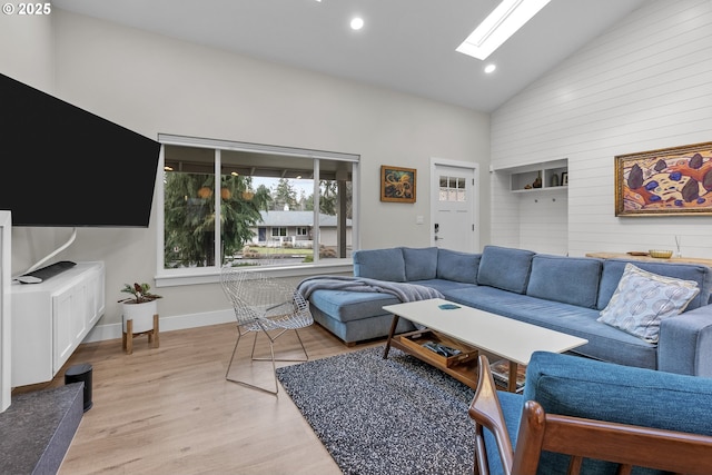 living room featuring high vaulted ceiling, light hardwood / wood-style floors, and a skylight