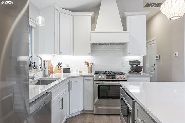 kitchen with sink, appliances with stainless steel finishes, white cabinets, and custom range hood