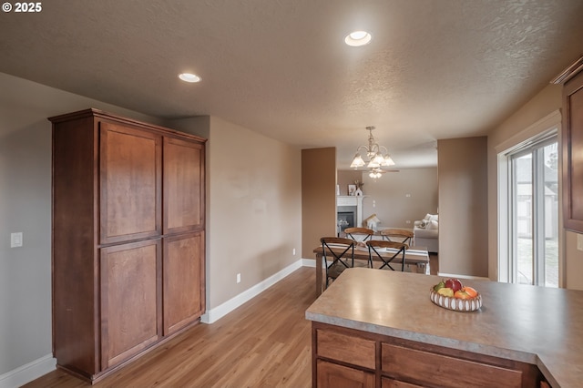 1989 S 12th St, Lebanon, OR 97355 - kitchen with light wood finished floors, brown cabinetry, pendant lighting, a textured ceiling, and a chandelier