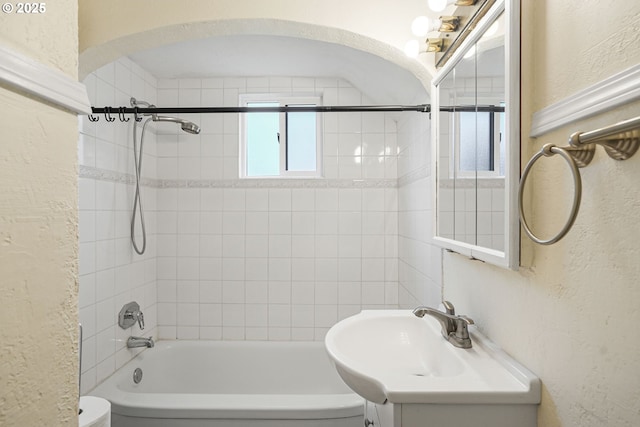 bathroom with a textured wall, bathing tub / shower combination, and vanity