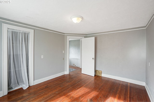 unfurnished bedroom with dark wood-type flooring, visible vents, ornamental molding, and baseboards