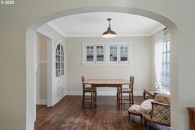 dining area featuring baseboards, arched walkways, wood finished floors, and ornamental molding