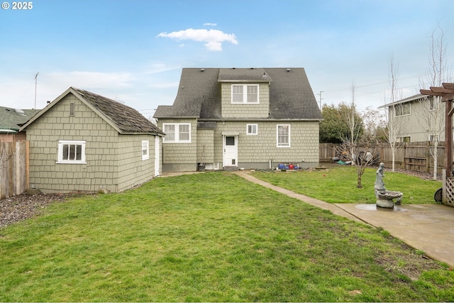 rear view of house featuring a yard, a fenced backyard, and an outdoor structure