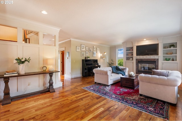 1046 NW Deerfern Loop, Camas, WA 98607 - living area with crown molding, wood finished floors, a glass covered fireplace, and built in shelves