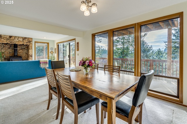 carpeted dining area featuring plenty of natural light and a wood stove