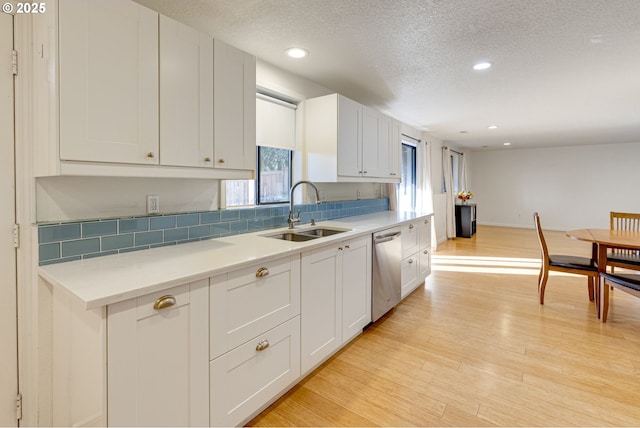 kitchen with sink, light hardwood / wood-style flooring, white cabinetry, a textured ceiling, and stainless steel dishwasher