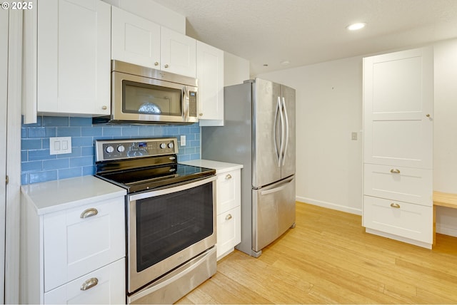 kitchen with appliances with stainless steel finishes, white cabinets, and decorative backsplash