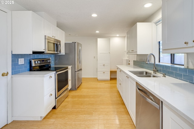 kitchen featuring white cabinetry, appliances with stainless steel finishes, sink, and light hardwood / wood-style floors