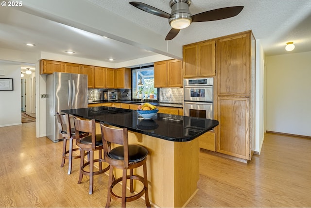 kitchen featuring a kitchen bar, sink, appliances with stainless steel finishes, a kitchen island, and backsplash