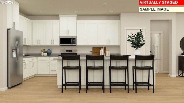 kitchen featuring a breakfast bar area, white cabinetry, stainless steel appliances, a kitchen island, and light wood-type flooring