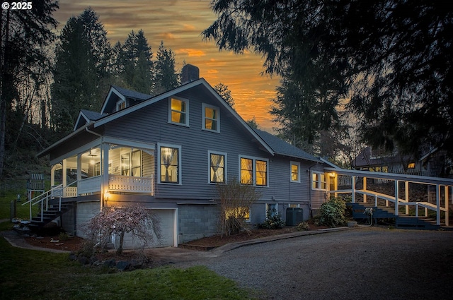 301 W Walnut St, Winlock, WA 98596 - back of house at dusk with an attached garage, a chimney, central AC unit, and driveway