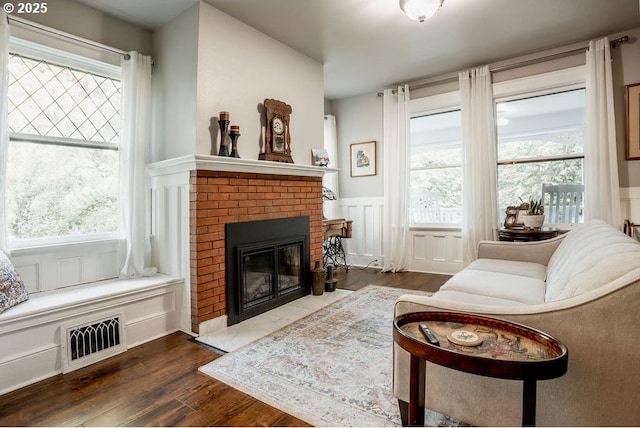 301 W Walnut St, Winlock, WA 98596 - living area featuring a wainscoted wall, wood finished floors, a brick fireplace, plenty of natural light, and a decorative wall