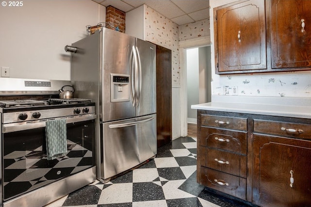 301 W Walnut St, Winlock, WA 98596 - kitchen featuring stainless steel appliances, dark floors, dark brown cabinets, light countertops, and a paneled ceiling