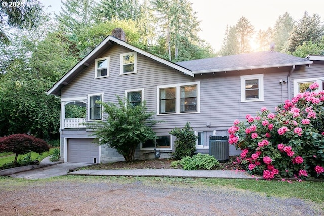 301 W Walnut St, Winlock, WA 98596 - view of front of house featuring concrete driveway, a chimney, an attached garage, cooling unit, and a shingled roof