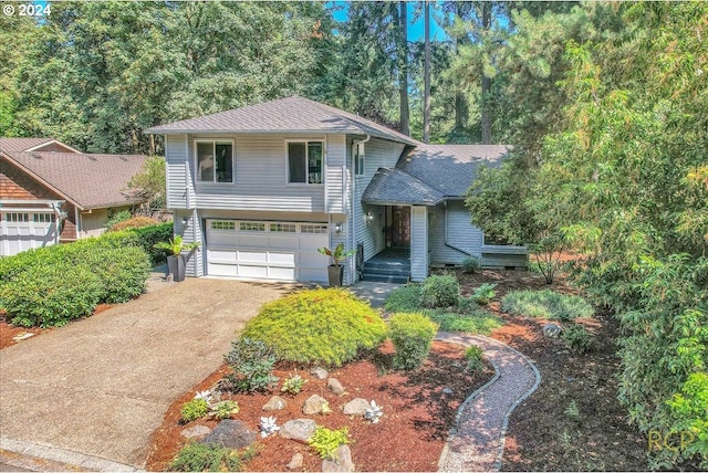 split level home with a shingled roof, driveway, and an attached garage