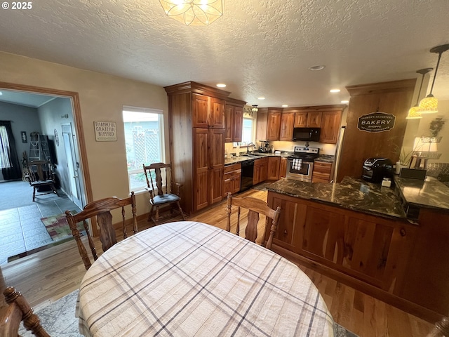 405 1st St, La Grande, OR 97850 - kitchen featuring black appliances, brown cabinets, light wood-type flooring, a textured ceiling, and recessed lighting
