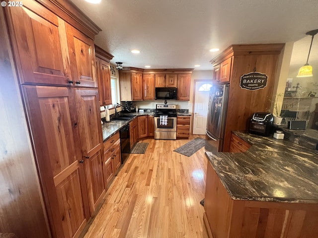 405 1st St, La Grande, OR 97850 - kitchen with black appliances, a sink, light wood-style floors, brown cabinets, and dark stone countertops