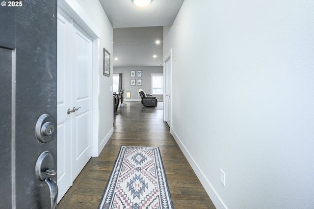 hall with dark wood-style flooring and baseboards