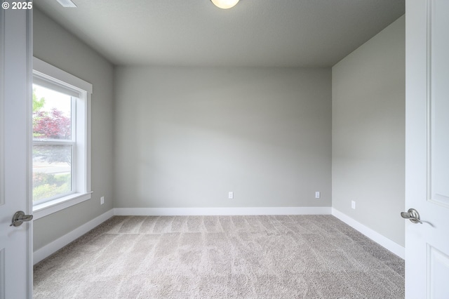 carpeted empty room featuring baseboards