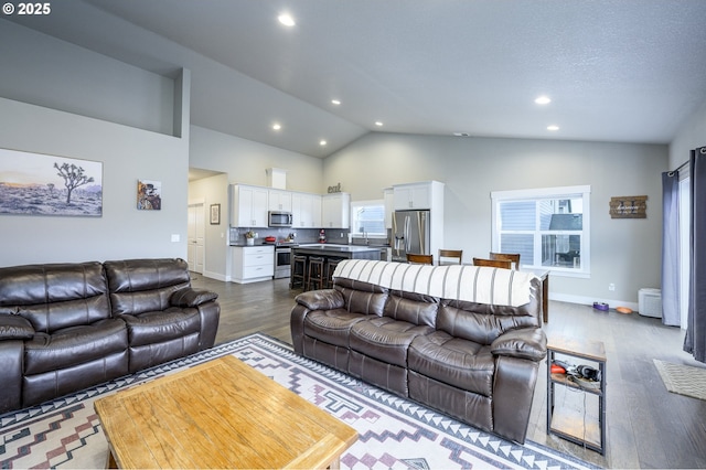 living area with dark wood-style flooring, high vaulted ceiling, recessed lighting, and baseboards