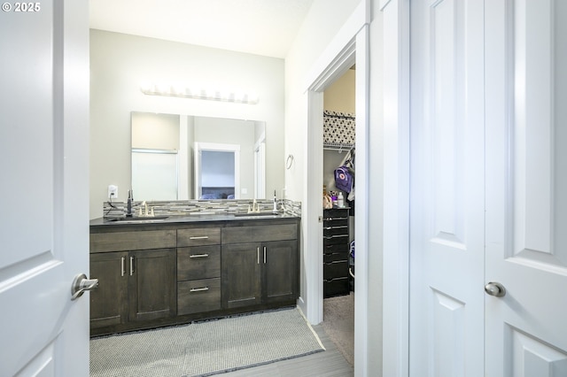 full bath with double vanity and a spacious closet