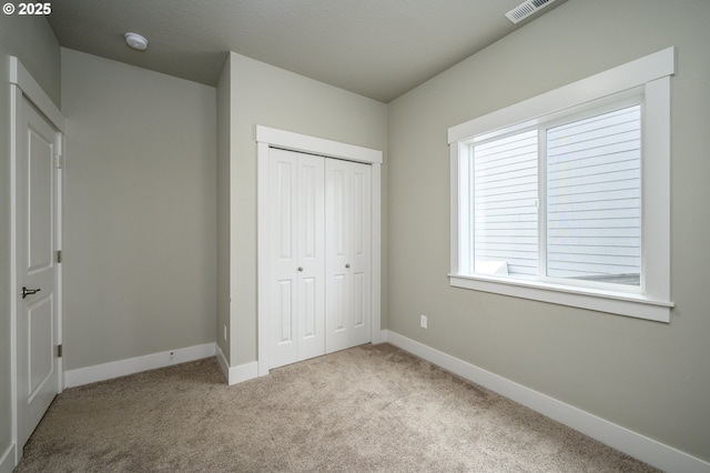 unfurnished bedroom featuring carpet floors, a closet, and baseboards