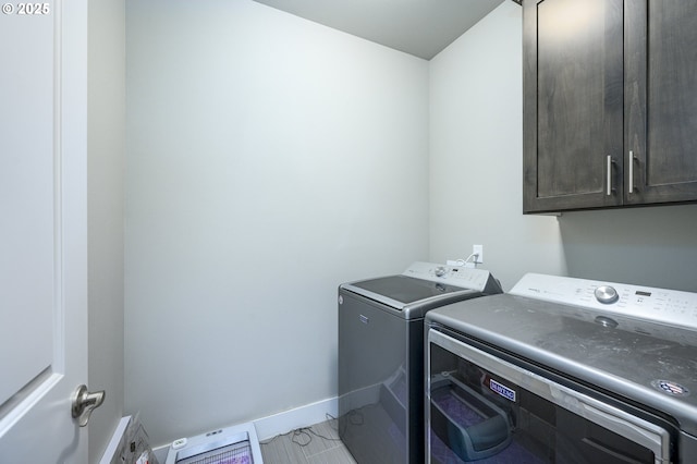 clothes washing area with cabinet space, separate washer and dryer, and baseboards
