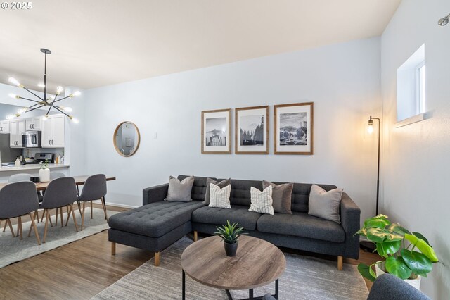 living area with baseboards, a notable chandelier, and wood finished floors