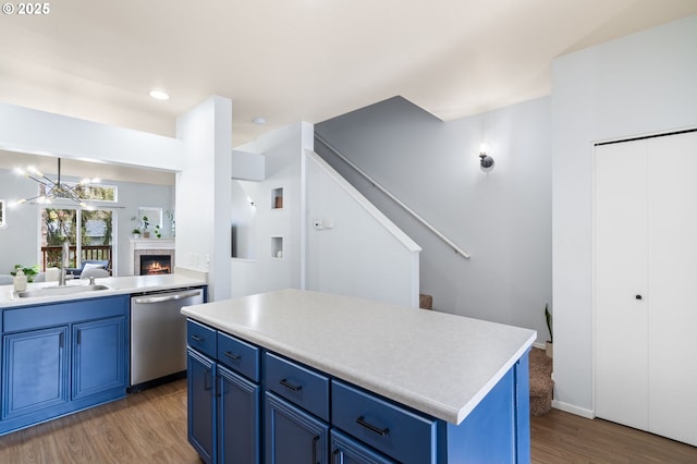 kitchen featuring blue cabinetry, dishwasher, light countertops, and a sink