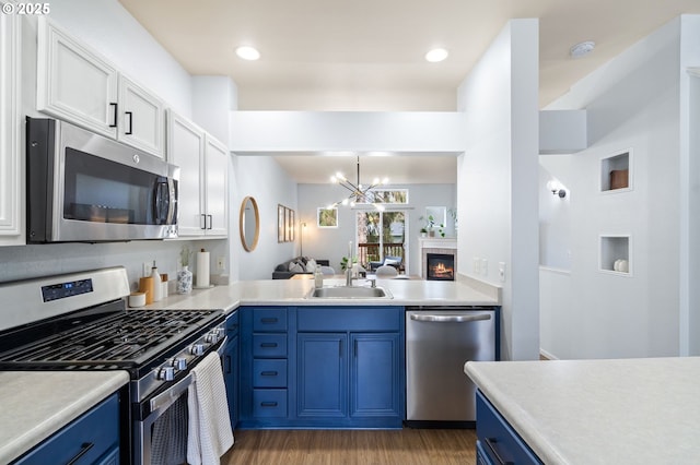 kitchen featuring blue cabinetry, stainless steel appliances, light countertops, and a sink