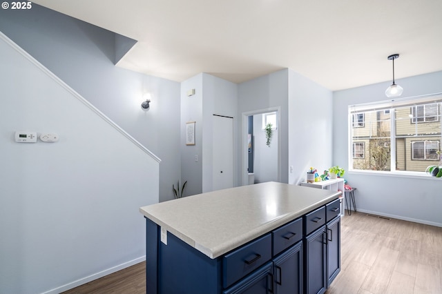 kitchen with baseboards, light countertops, light wood-style floors, decorative light fixtures, and blue cabinets