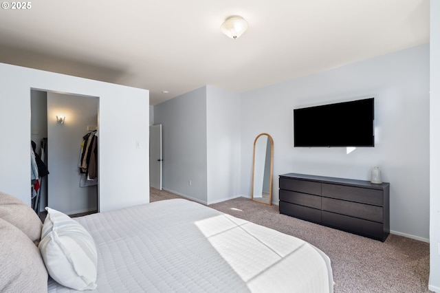 bedroom featuring a walk in closet, baseboards, and carpet flooring