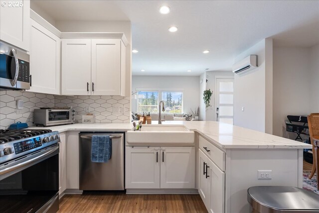 16615 SE Sunshower Pl, Happy Valley, OR 97086 - kitchen featuring appliances with stainless steel finishes, a sink, a wall mounted AC, a peninsula, and light wood-style floors