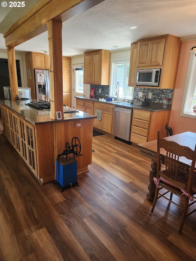 kitchen featuring a wealth of natural light, backsplash, stainless steel appliances, and dark wood-style flooring