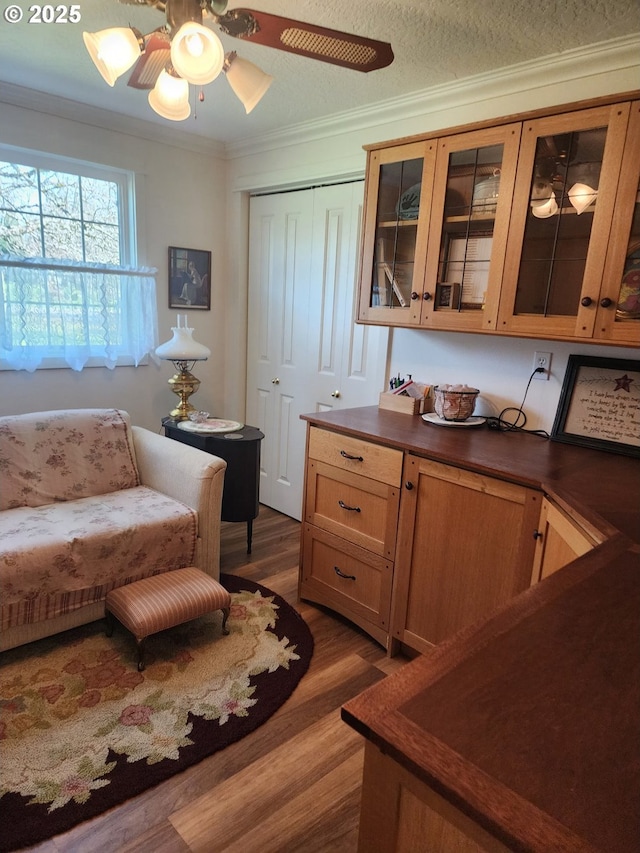 living area featuring a ceiling fan, a textured ceiling, wood finished floors, and ornamental molding