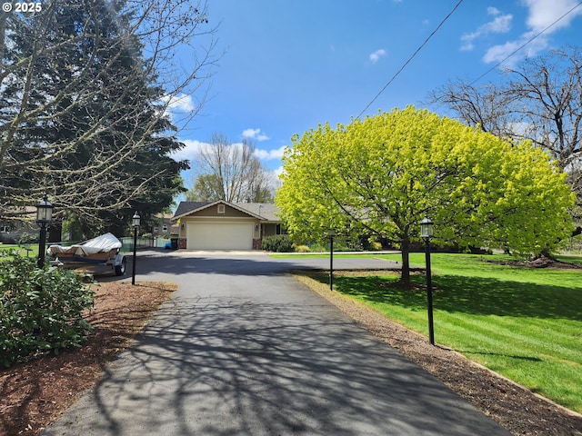 view of front of home featuring an attached garage, driveway, and a front lawn