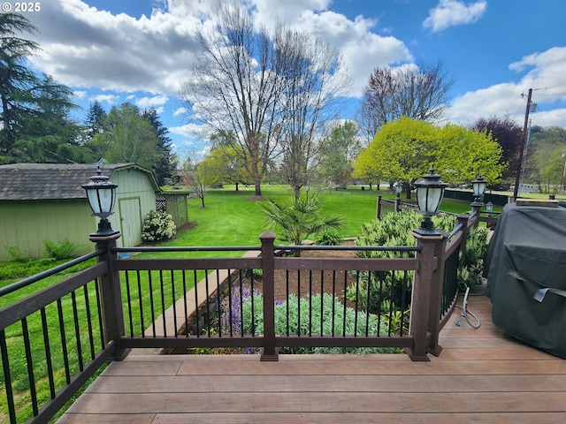 deck featuring a shed, a yard, a grill, and an outbuilding