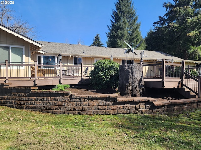 rear view of property featuring board and batten siding, a yard, stairway, roof with shingles, and a deck