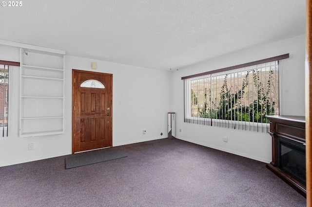 foyer featuring plenty of natural light, dark carpet, and a textured ceiling