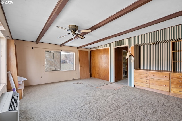 interior space featuring carpet, a ceiling fan, and beamed ceiling