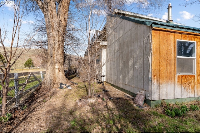 view of side of property featuring an outbuilding, metal roof, and fence