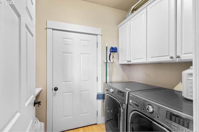 washroom featuring cabinets, light hardwood / wood-style flooring, and washing machine and clothes dryer