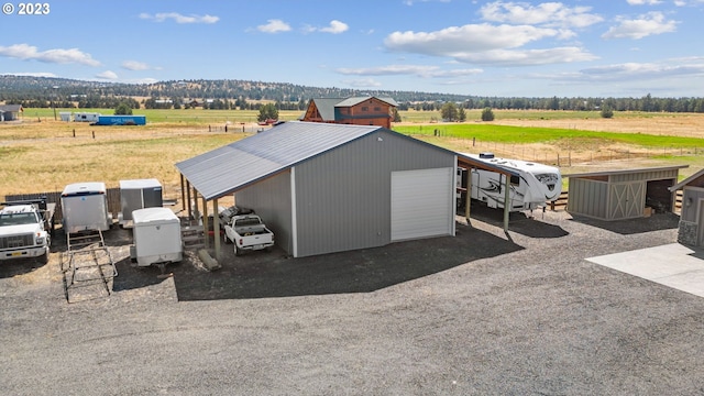 view of outdoor structure with a rural view, a garage, and a mountain view